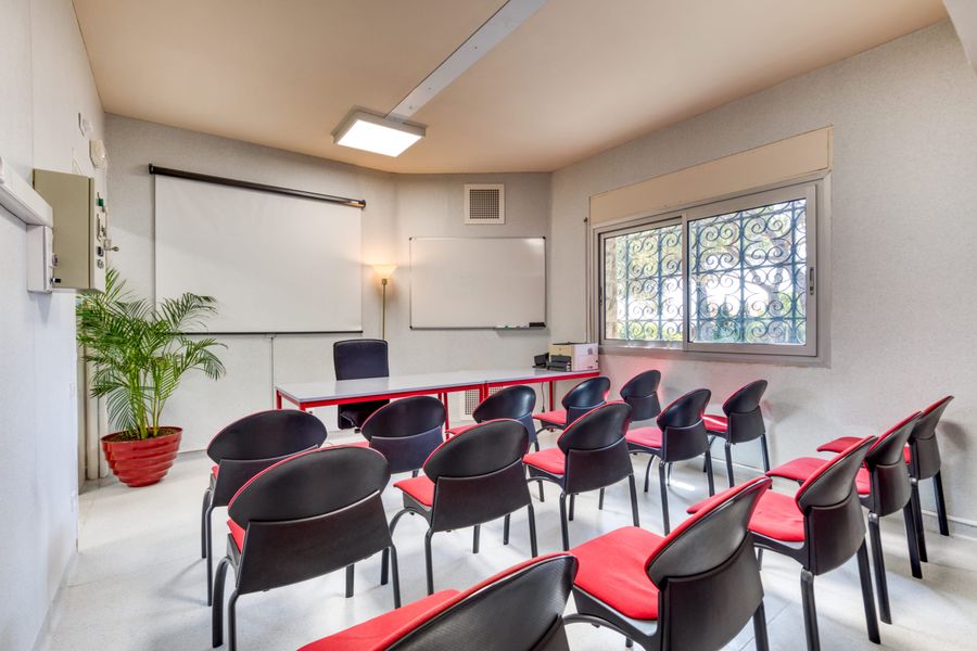 La salle de réunion du cabinet Syndiclair préparée pour une assemblée générale : rangées de chaises face à la table de séance, au tableau et à l'écran de projection