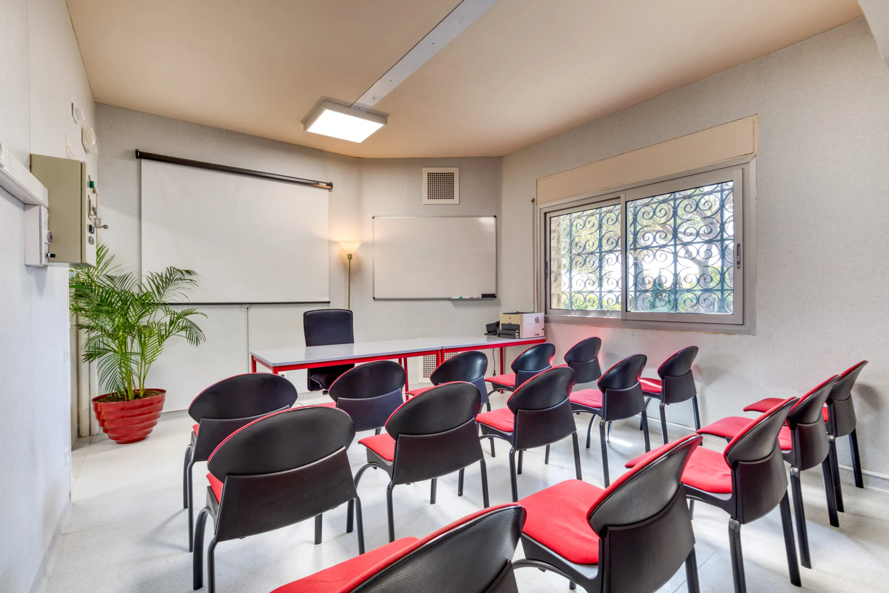 La salle de réunion du cabinet Syndiclair préparée pour une assemblée générale : rangées de chaises face à la table de séance, au tableau et à l'écran de projection